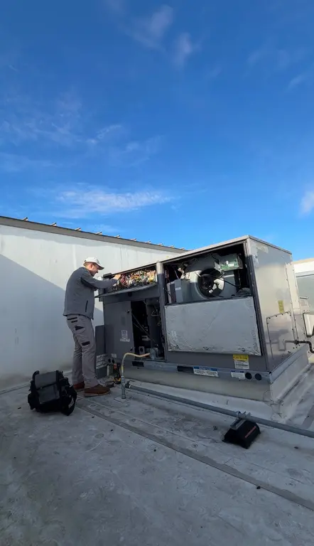 North Breeze technician inspecting RTU control board on commercial rooftop
