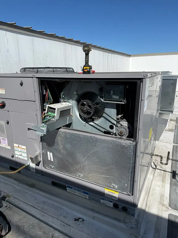 RTU blower compartment opened showing belt drive and VFD