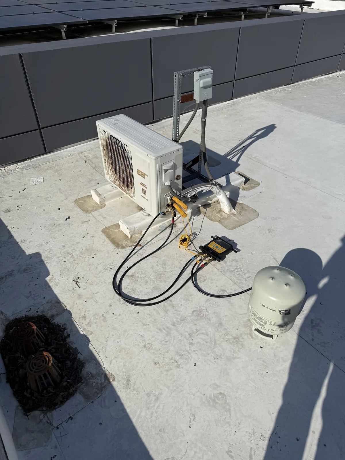 WhisperKOOL outdoor condenser with manifold gauges connected for refrigerant charging by weight