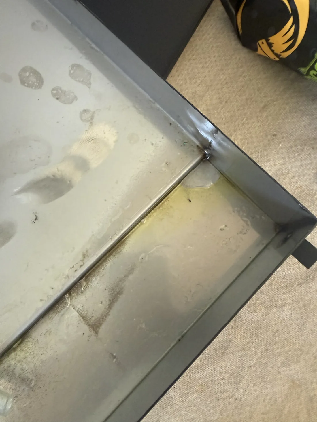 Oil residue at WhisperKOOL evaporator drain pan corner confirming refrigerant leak