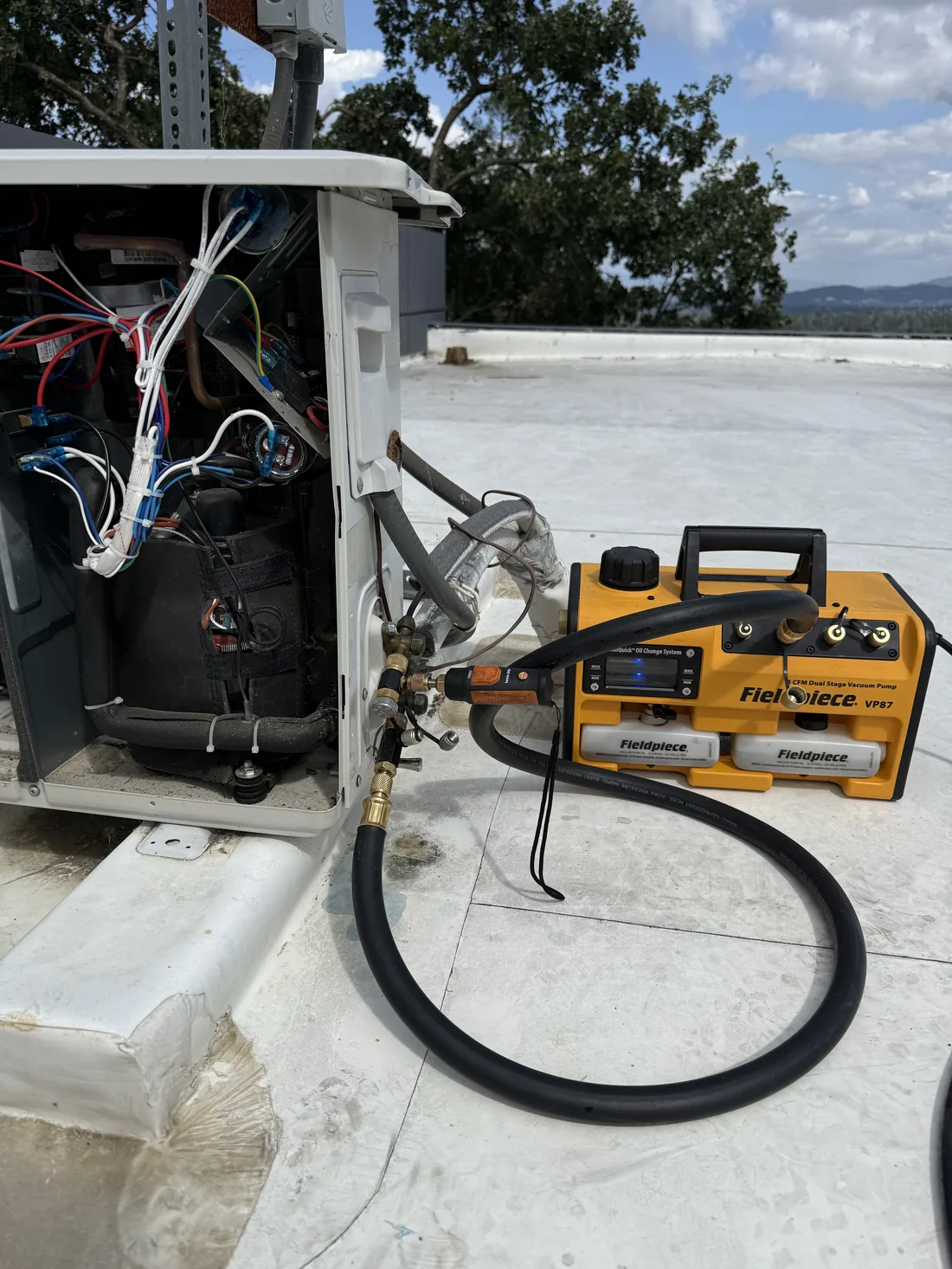 Fieldpiece dual-stage vacuum pump connected to WhisperKOOL outdoor condenser for system evacuation