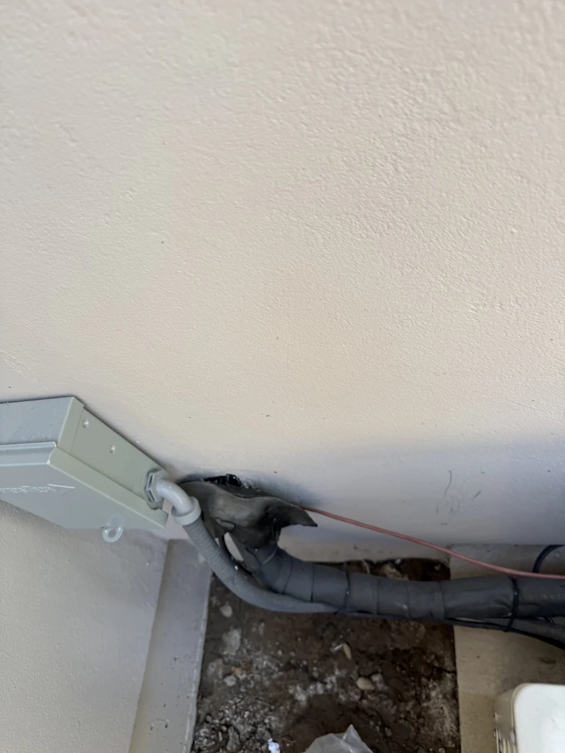Damaged line set wall penetration on bad wine cellar cooling install with torn insulation and exposed wires