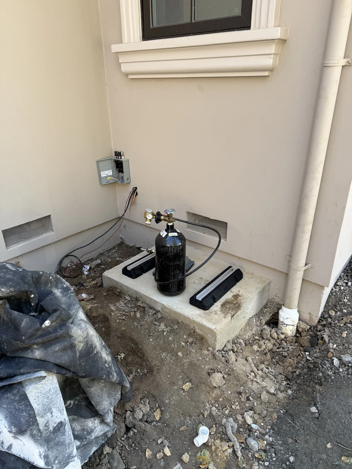 Outdoor condenser pad with new vibration isolation pads installed and nitrogen cylinder positioned for line set pressure purge during wine cellar cooling rework